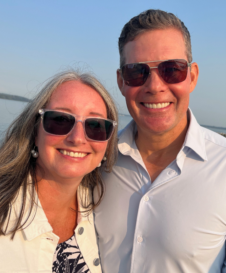 two people smiling in front of the ocean