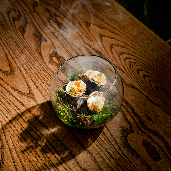 a glass of smoked oysters displayed elegantly