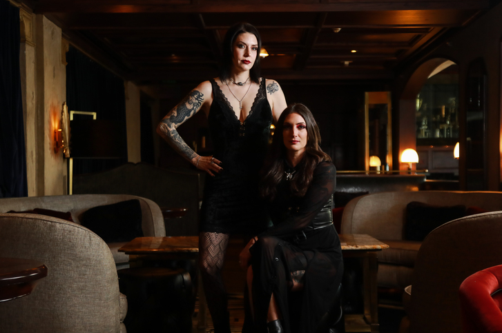 Co-founders Erin Hayes and Kelsey Ramage stand and sit together with a dark restaurant backdrop
