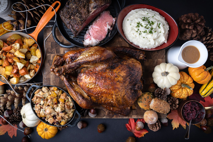 Same as featured. Close up over top shot of table with Turkey, mashed potatoes stuffing and beef with gourds for decoration