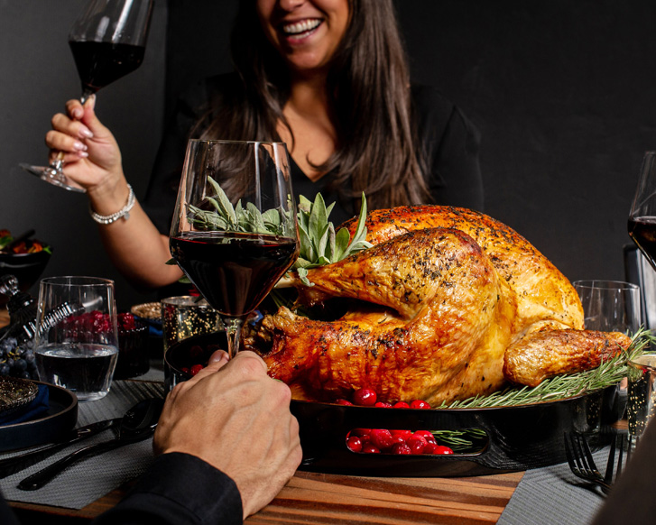 Roast turkey with someone in the background drinking wine and someone in the foreground