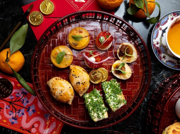 Afternoon tea tray spread with tarts, eggs, sandwiches, and more.