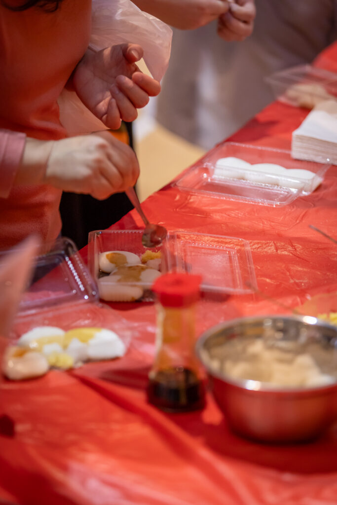 Fresh mochi being added to containers and drizzled with soy sauce. 