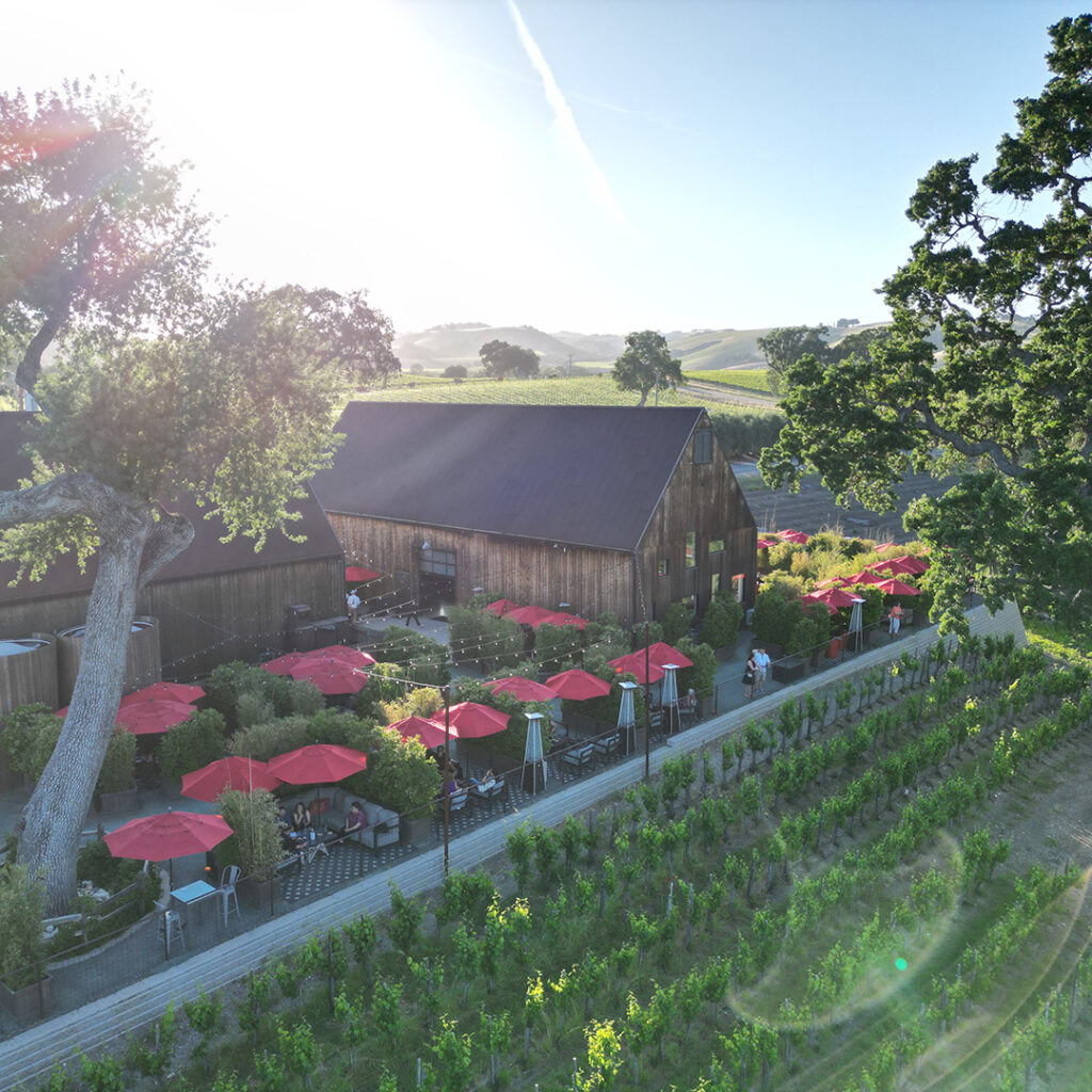 An overhead outdoor shot of a stunning winery with little red umbrellas on the patio.