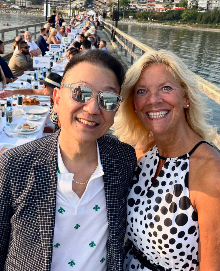 two people smiling in front of a long table