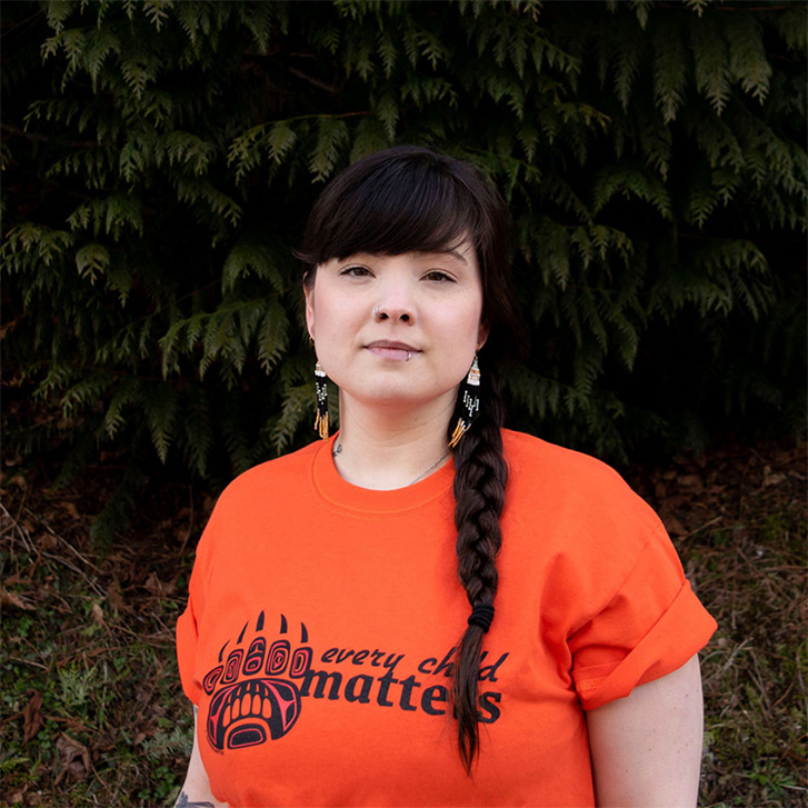 Woman wearing an orange shirt with a black design of a bear paw.