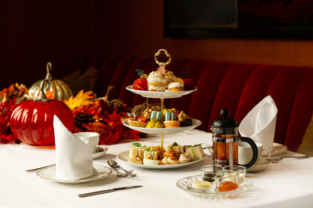 An elegant tea on a three-tier serving tray with pumpkins surrounding.