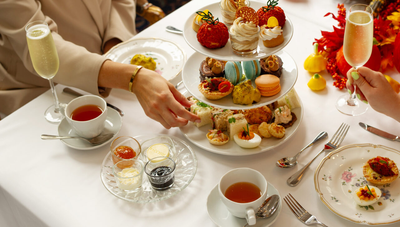 A person reaches for a treat off a colourful three-tier tea service.