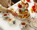 A person reaches for a treat off a colourful three-tier tea service.