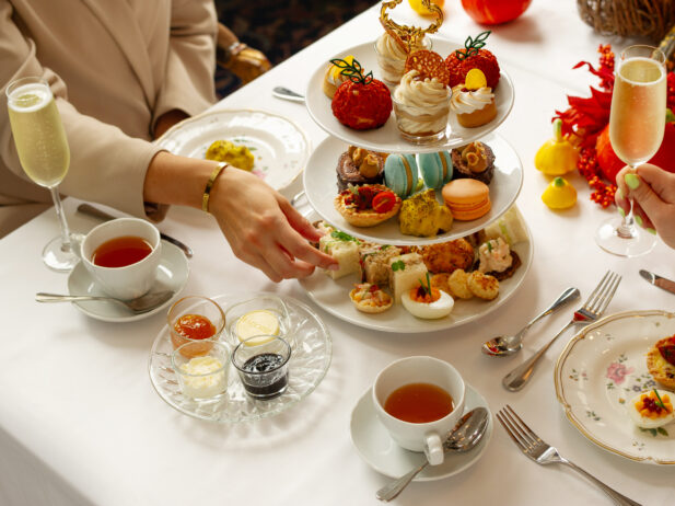 A person reaches for a treat off a colourful three-tier tea service.