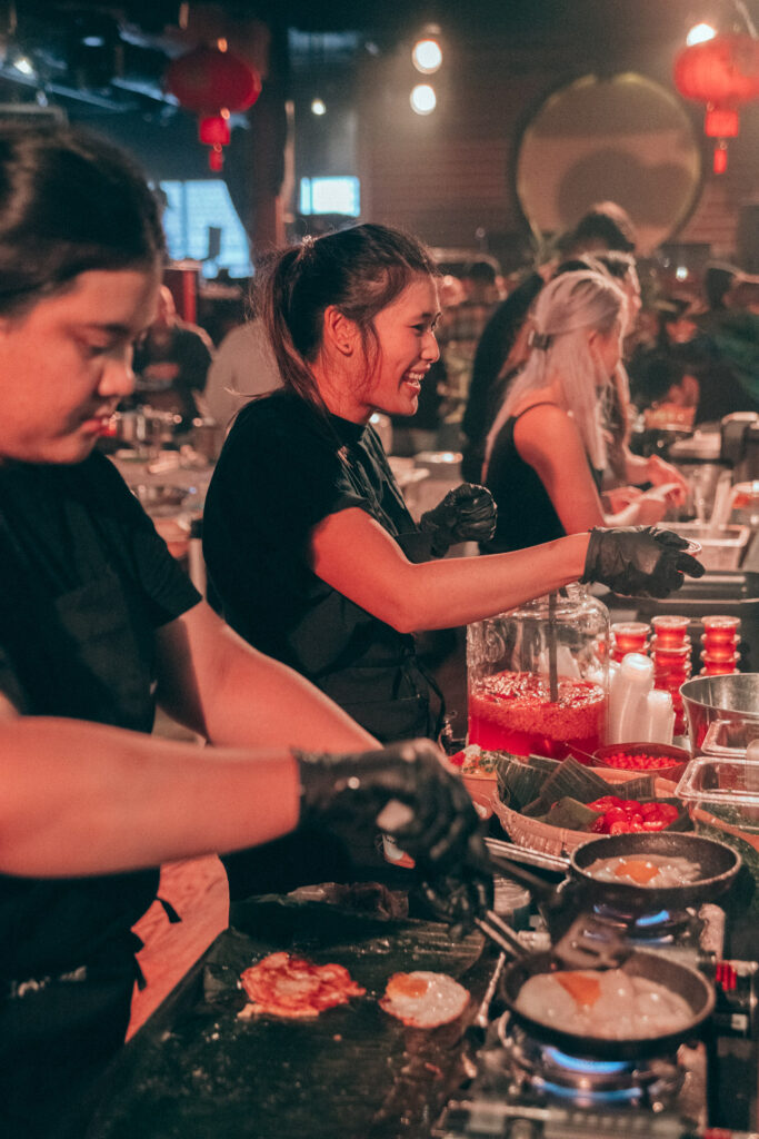 A trio in black t-shirts fry eggs to serve at a food pop-up. 