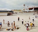 People walking to and from passenger planes on an airport tarmac.