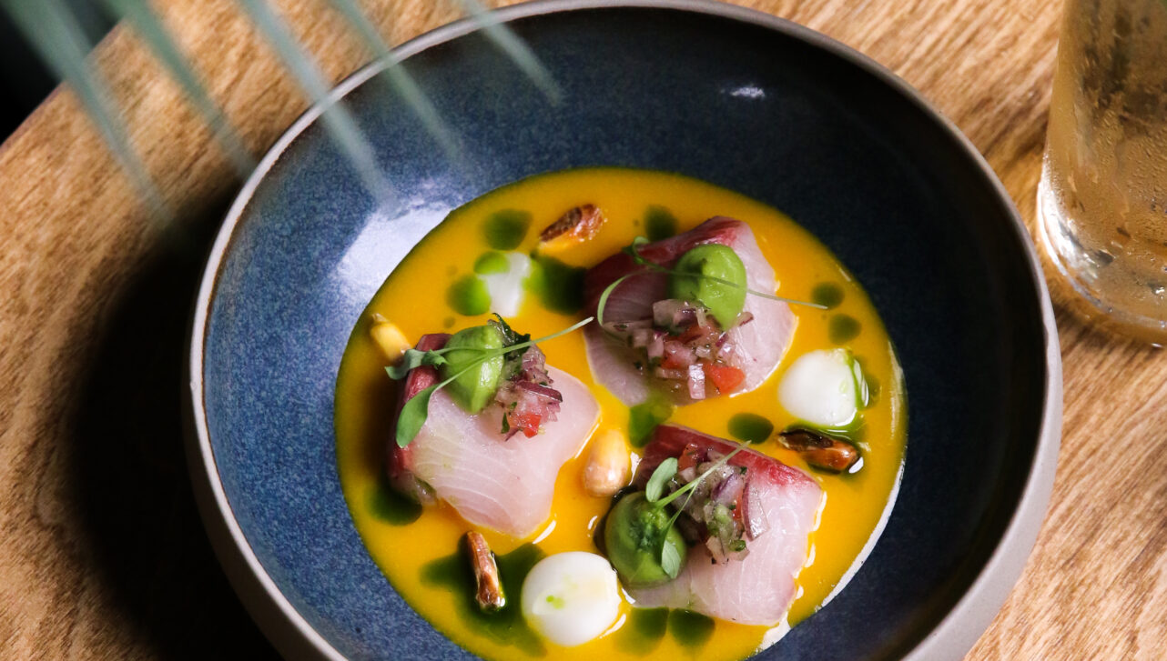 An artfully plated raw seafood dish atop a natural wood table.