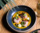 An artfully plated raw seafood dish atop a natural wood table.