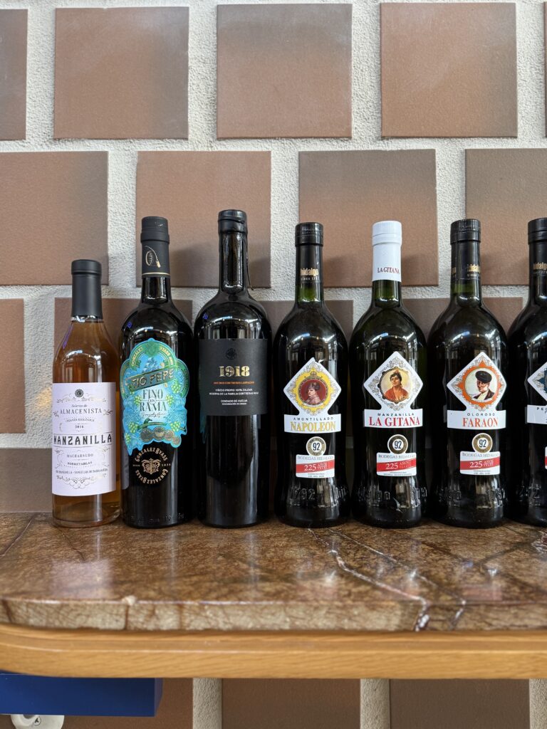 Bottles of sherry lined up against a wall on a countertop. 