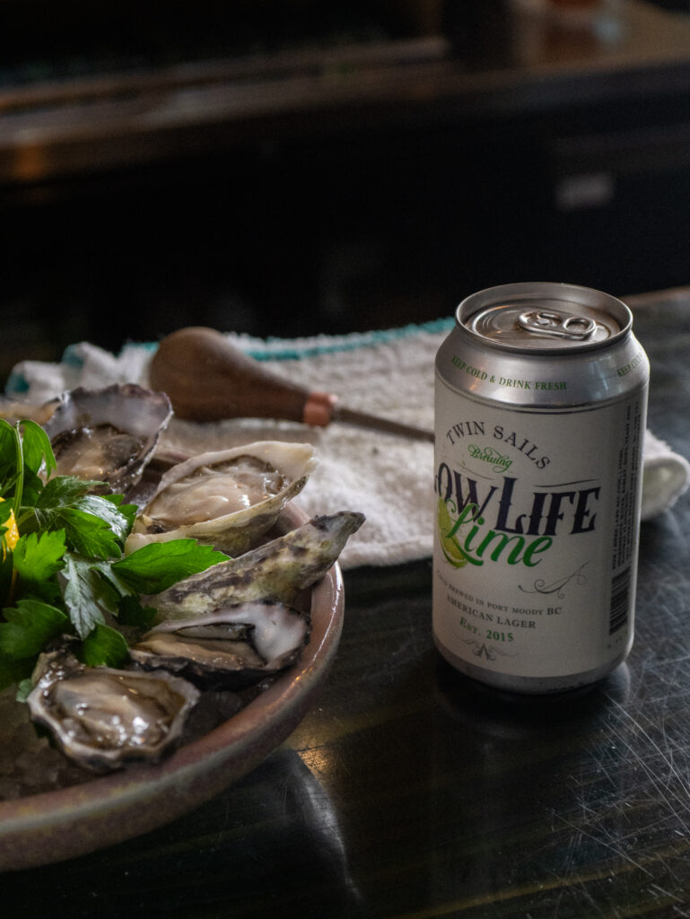 A plate of fresh oysters with a can of beer alongside.