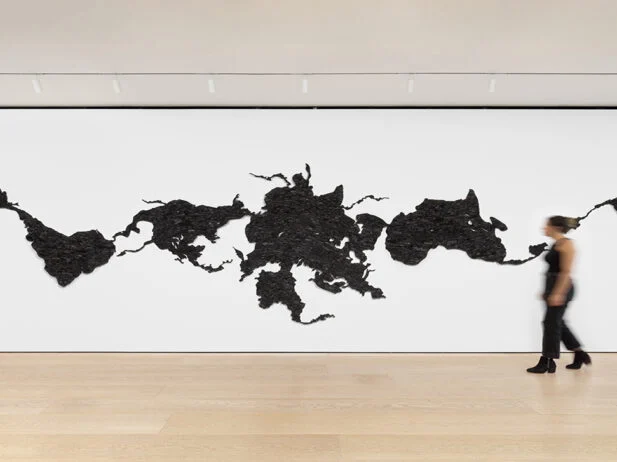 Woman walks by large, wall-mounted map of the world.