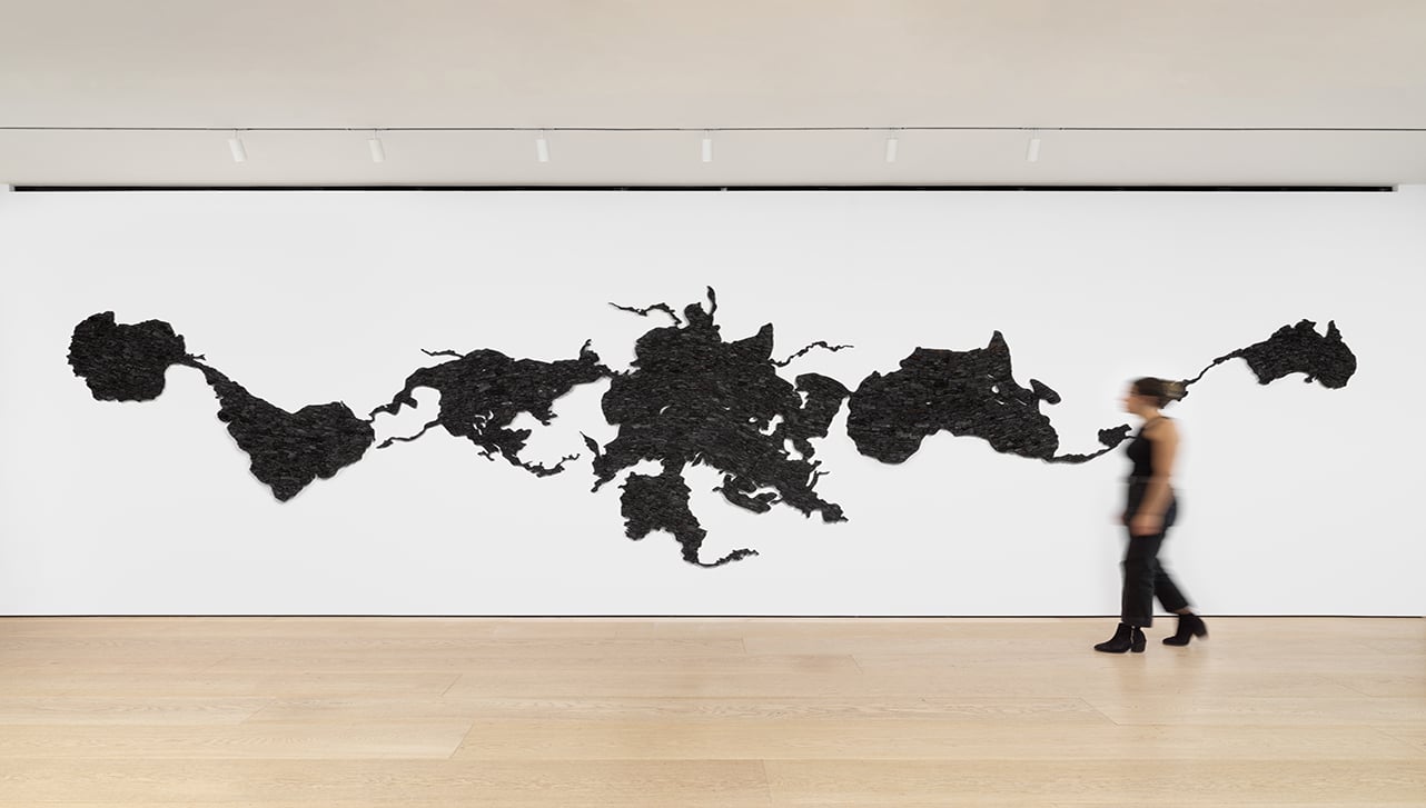 Woman walks by large, wall-mounted map of the world.