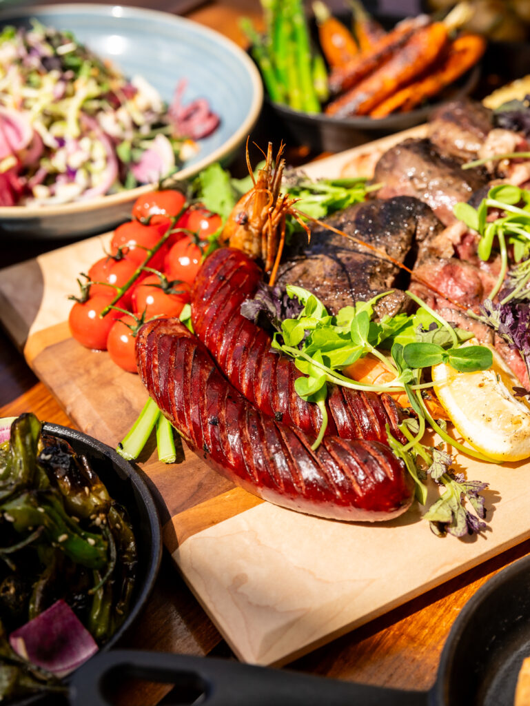 Tomatoes, sausages, and an assortment of food items on a wooden board