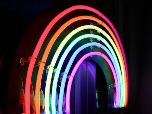 A rainbow made out of neon lights in front of a dark backdrop