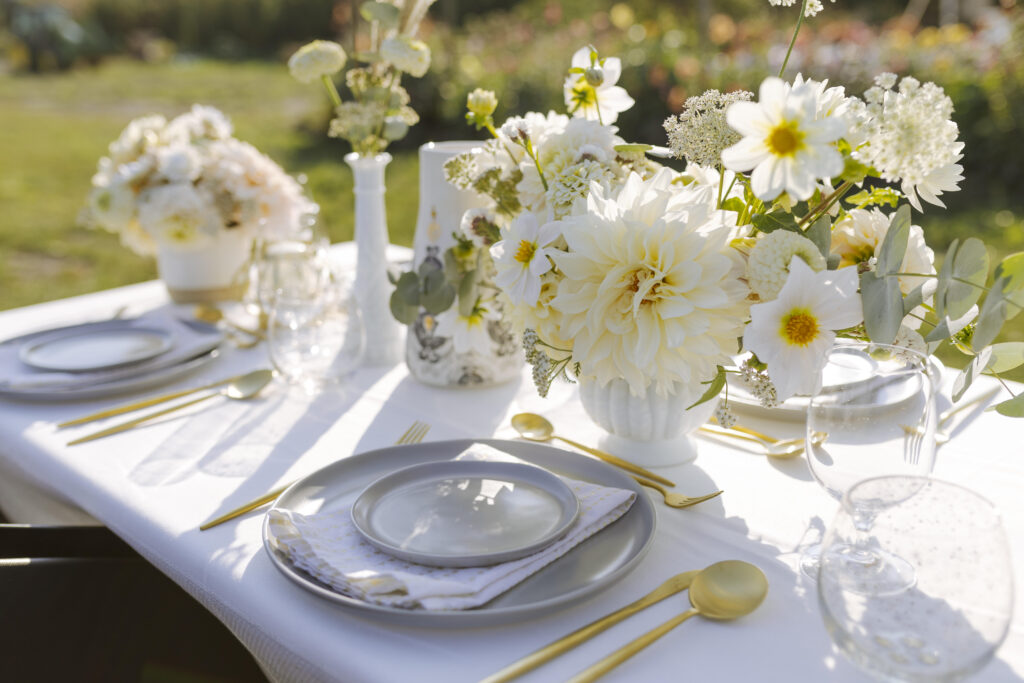 A pretty outdoor table setting with fresh white flowers on a white tablecloth. 