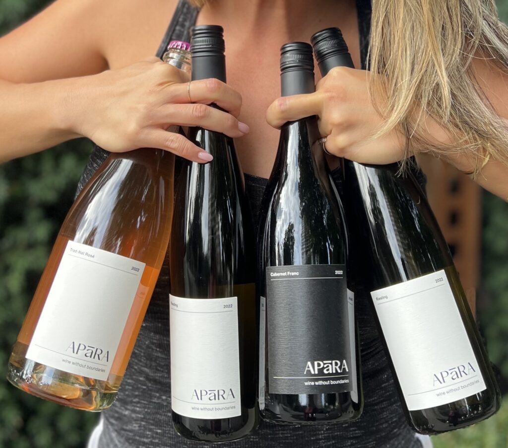 A person holds four bottles of wine.