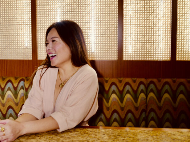 amelie sits in a restaurant booth laughing