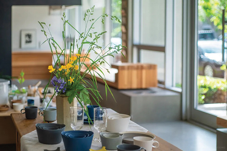 a vase of flowers and beautiful ceramics on a table in a lovely store