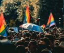 A crowd at a Pride Parade with rainbow flags in the background