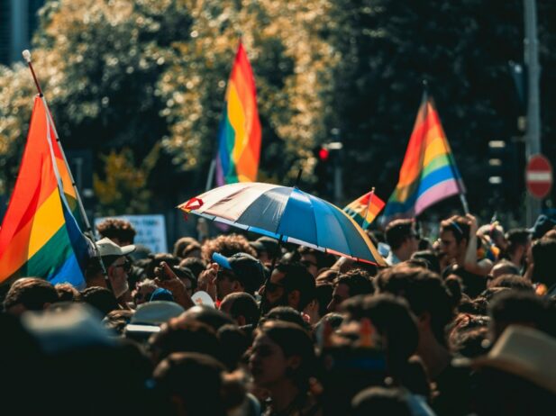 A crowd at a Pride Parade with rainbow flags in the background