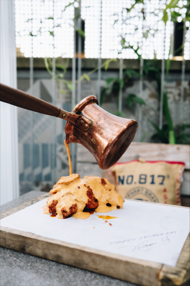 a piece of shnitzel on a plate, being doused in sauce